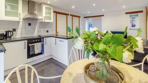 Una cocina moderna con armarios blancos, una estufa y un comedor con mesa y sillas.