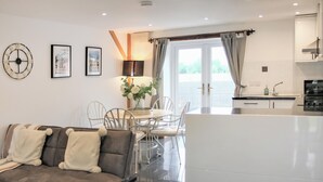 Una sala de estar moderna con sofá, mesa de comedor, sillas y una cocina con vistas.