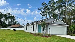 A single-story house with a garage, a small front yard, and a white fence. - Charming 3-bedroom house with WiFi, AC in terrific Palm Coast (Palm Coast)