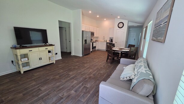 A living room with a TV, a sofa, and a dining area with a table and chairs. - Charming 3-bedroom house with WiFi, AC in terrific Palm Coast (Palm Coast)