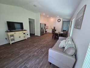 Ein Wohnzimmer mit Fernseher, einer Couch und einem Essbereich mit Tisch und Stühlen.