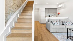 A staircase leading to a living area with a sofa and a kitchen in the background. - GuestReady - Charming Retreat near the Cathedral (Vila Nova de Gaia)