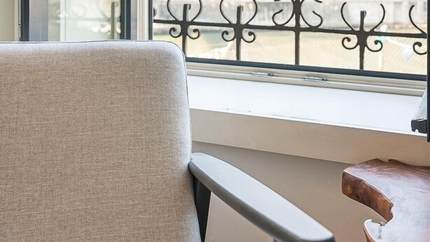 A room with a view of a cityscape through a window, a chair, a table, and a decorative metal railing. - GuestReady - Charming Retreat near the Cathedral (Vila Nova de Gaia)