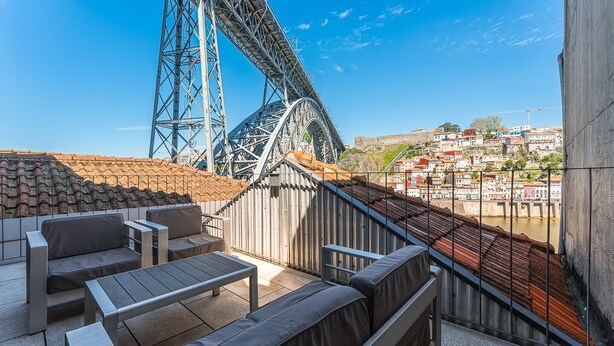 A terrace with seating, a view of a bridge, and a cityscape in the background. - GuestReady - Riverside Retreat with Terrace Views (Vila Nova de Gaia)