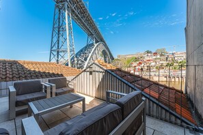 A terrace with seating, a view of a bridge, and a cityscape in the background. - GuestReady - Riverside Retreat with Terrace Views (Vila Nova de Gaia)