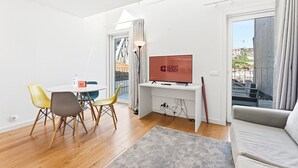 A modern living room with a dining area, a TV, and a sofa. - GuestReady - Riverside Retreat with Terrace Views (Vila Nova de Gaia)