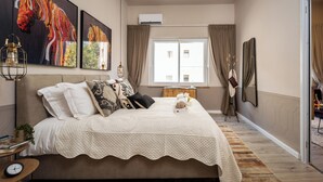 A bedroom with a large bed, a bedside table with a clock, and a window with curtains. - Charming 1-bedroom apartment with WiFi, AC in gorgeous Jerusalem (Jerusalem)