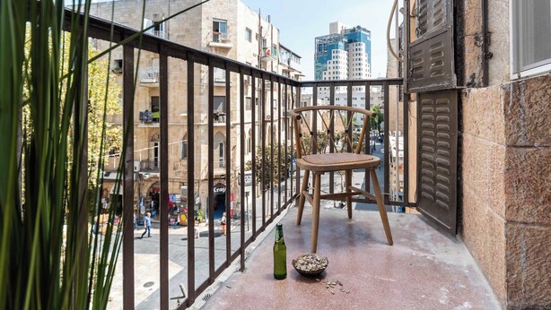 A balcony with a chair, a bottle, and a bowl of cereal. - Charming 1-bedroom apartment with WiFi, AC in gorgeous Jerusalem (Jerusalem)