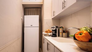 A compact kitchen with a white refrigerator, a sink, and a bowl of vegetables. - Charming 1-bedroom apartment with WiFi, AC in gorgeous Jerusalem (Jerusalem)