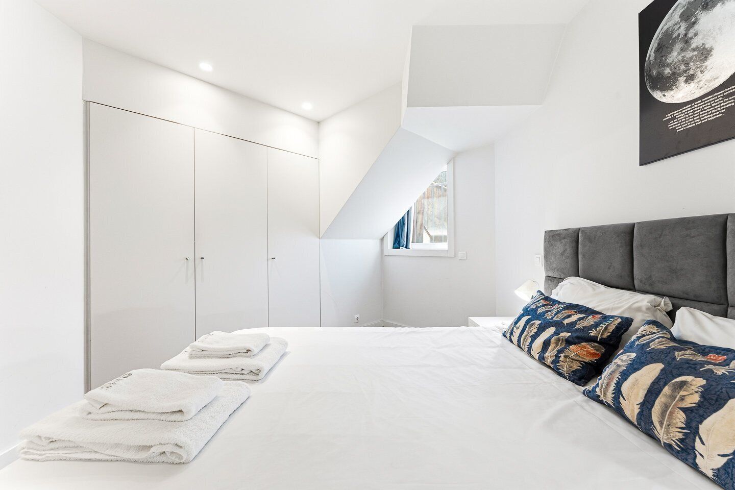 A bedroom with a bed, pillows, a window, and a wardrobe.