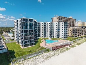 A modern multi-story hotel with a rooftop pool and beach access.