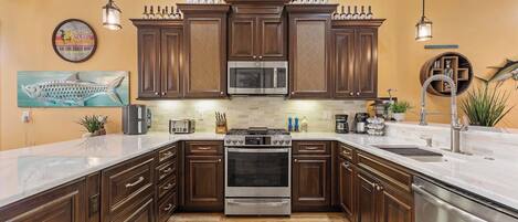 A kitchen with dark wooden cabinets, stainless steel appliances, and a white countertop.