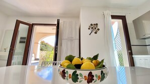 A room with a white table, a bowl of lemons, and a view of the outside. - Villasimius, Vacation House, with private garden, Casagora (Sardegna)
