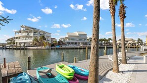 A waterfront property with a dock, kayaks, and a large house with multiple balconies. - Captain's Cove 4BR 3Bath  Water View, Pickleball, Private Beach, Heated Pool! (Pensacola)