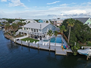 A waterfront property with a pool, dock, and multiple boats.