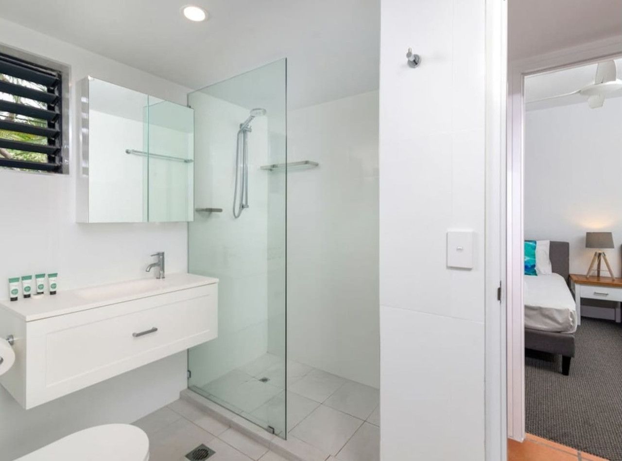 A modern bathroom with a glass shower enclosure, a white vanity with a mirror, and a toilet.