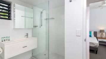 A modern bathroom with a glass shower enclosure, a white vanity with a mirror, and a toilet.