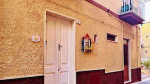 Un bâtiment doté d’une façade à motifs, d’une porte blanche et d’une petite fenêtre à cadre rouge.