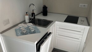 Une cuisine de taille réduite équipée d’un évier, d’une machine à café et d’un lave-vaisselle.