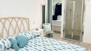 Une chambre à coucher comprenant un lit, une table de chevet, un miroir, une armoire et un espace douche.