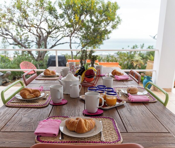 A wooden table set for breakfast with croissants, coffee, and fruit. - CT 385 - Faro's Soulrise Villa - Mojacar (Mojacar)