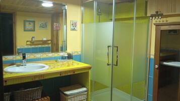 A bathroom with a glass-enclosed shower, a sink with a tiled backsplash, and wicker baskets.