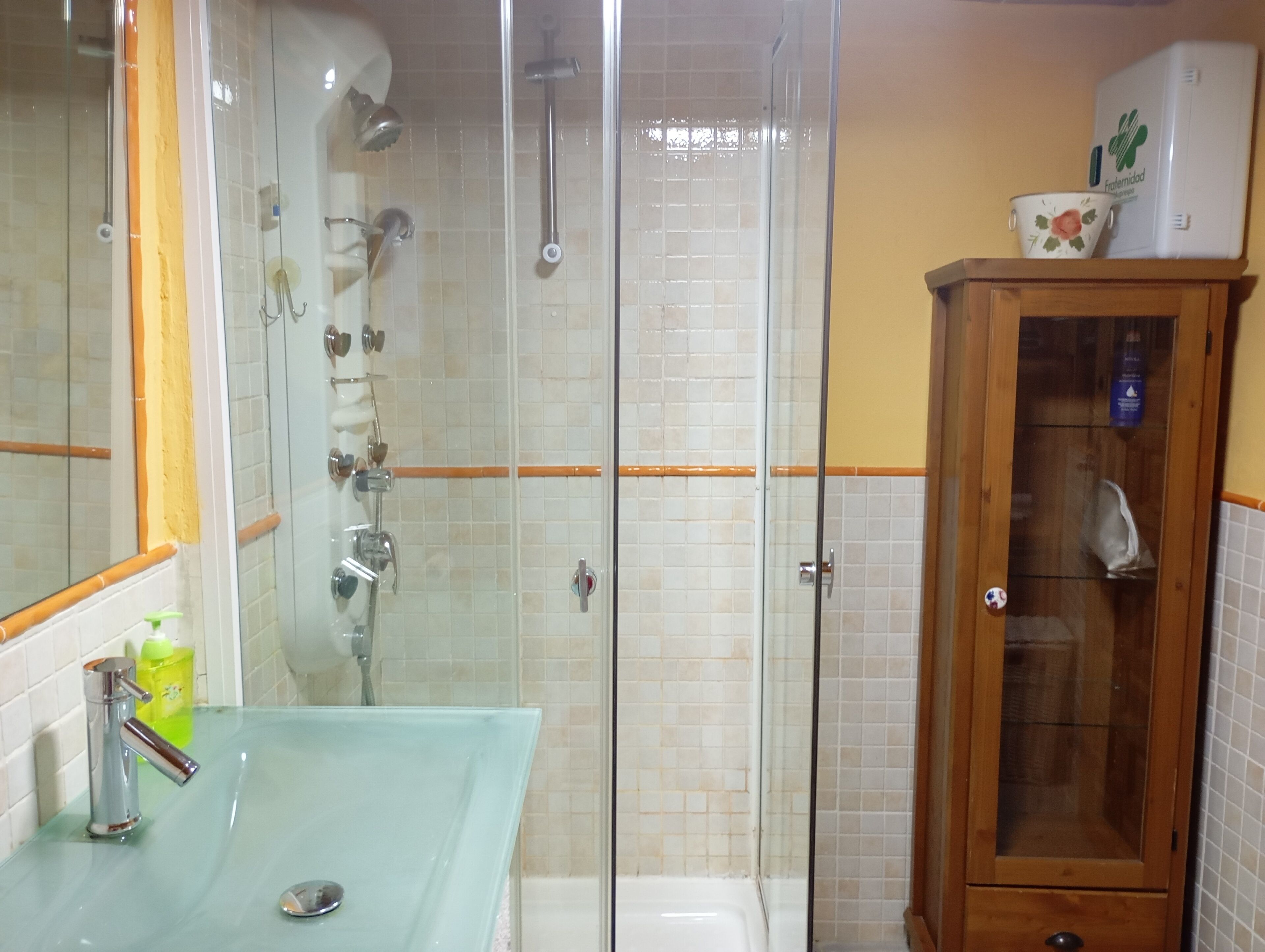 Une salle de bain avec une douche à parois de verre, un lavabo avec un miroir et un meuble en bois.