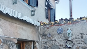 Un espacio de descanso al aire libre rústico, con paredes de piedra, sillas de metal y una pequeña mesa.