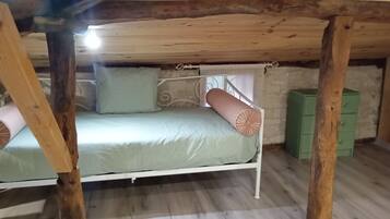 Een stapelbed in een rustieke kamer met houten balken, een groene kledingkast en een witte muur.