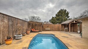 A backyard with a swimming pool, wooden fence, and outdoor seating. - Collins Family-friendly Texas Home With Private Pool (Garland)
