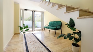A spacious living area with a green sofa, a potted plant, and a marble floor. - Opus Hotel (Berat)