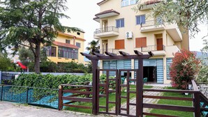 A multi-story residential building with a balcony, a gated entrance, and a small garden area. - Opus Hotel (Berat)