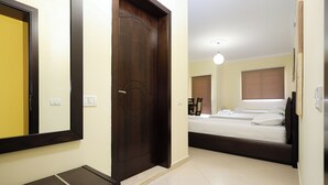 A bedroom with a bed, a bedside table, a mirror, and a door. - Opus Hotel (Berat)
