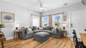Una sala moderna con un sofá modular, piso de madera y un ventilador de techo.