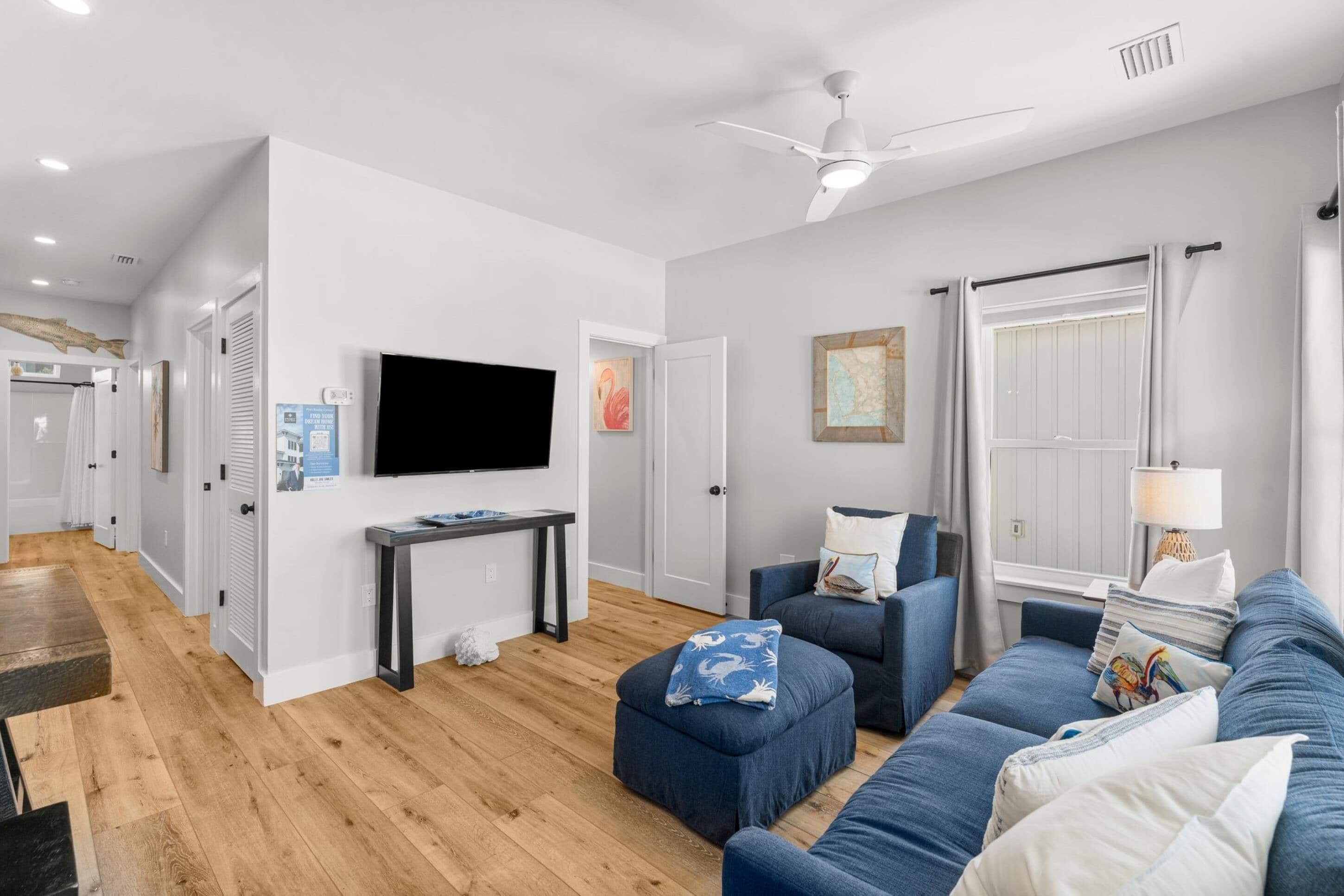A modern living room with a flat-screen TV, a sofa, a coffee table, and a lamp.