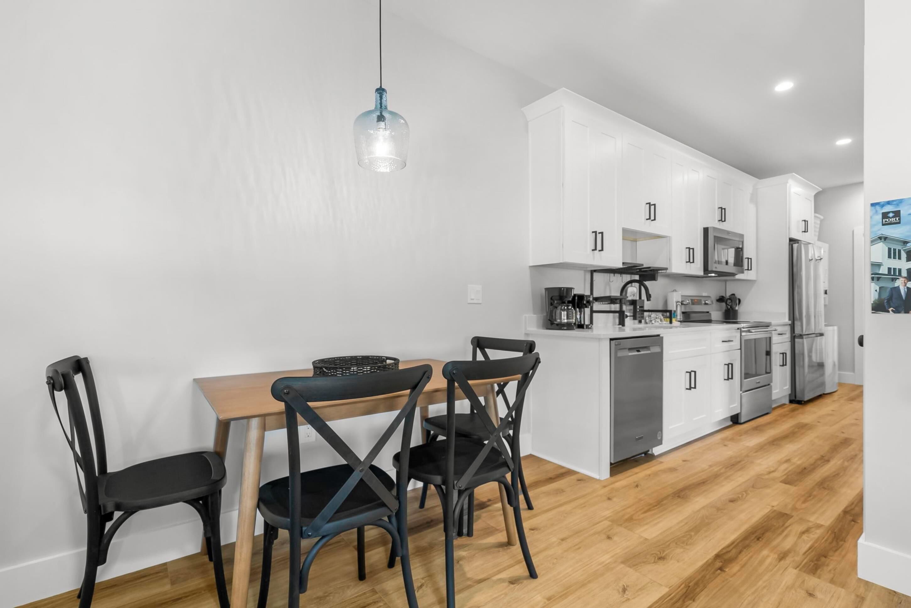 A modern kitchen with white cabinets, a wooden dining table, and black chairs.