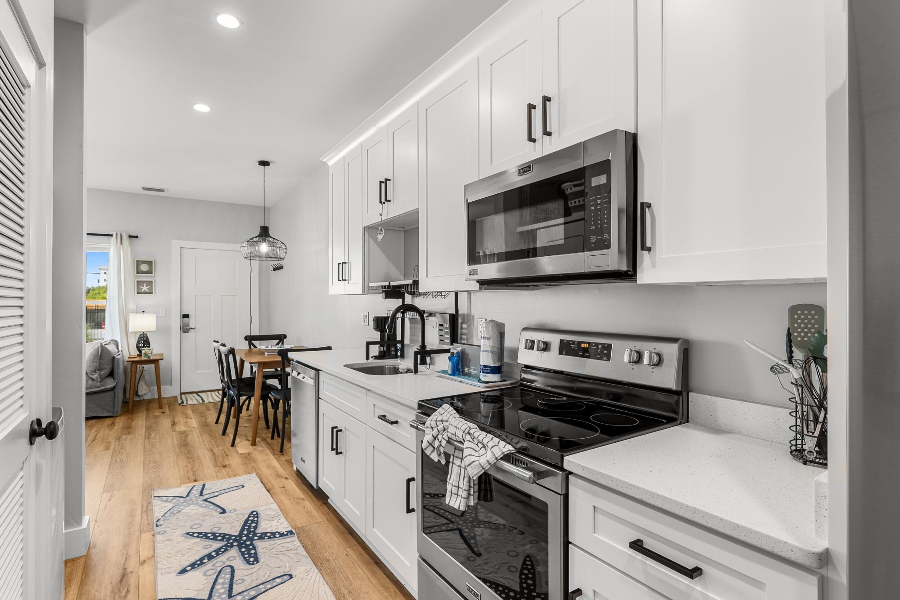 Una cocina moderna con armarios blancos, electrodomésticos de acero inoxidable y una mesa de comedor de madera.