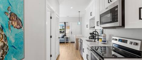 A modern kitchen with white cabinets, a microwave, and a stove.