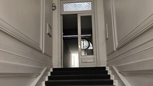 A grand staircase with a dark carpet, leading to a door with a decorative glass panel.