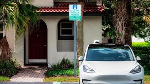Un véhicule électrique blanc est stationné dans un espace réservé à cet effet, et un panneau indique qu’il est uniquement destiné au stationnement des véhicules électriques pendant la recharge.