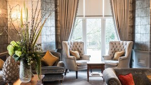 A spacious room with two armchairs, a sofa, a coffee table, and a decorative vase with greenery. - Forest Side Hotel (Ambleside)