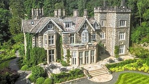 A large stone manor with multiple chimneys, surrounded by lush greenery and a well-maintained lawn. - Forest Side Hotel (Ambleside)
