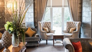 A spacious room with two armchairs, a sofa, a coffee table, and a decorative vase with greenery. - Forest Side Hotel (Ambleside)