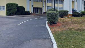 A yellow building with a covered entrance, large windows, and a parking lot. - University Inn Gainesville (Gainesville)