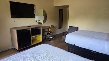 A hotel room with two beds, a desk with a chair, a television, and a mirror.