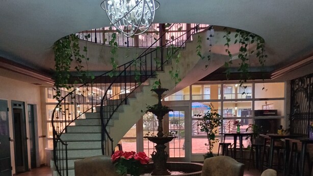 A dining area with a round table, chairs, a chandelier, and a spiral staircase with a view to the outside. - University Inn Gainesville (Gainesville)