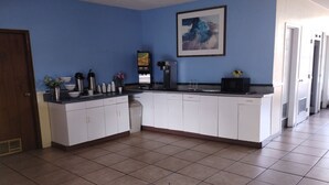 A kitchen with white cabinets, a coffee machine, and a microwave. - University Inn Gainesville (Gainesville)