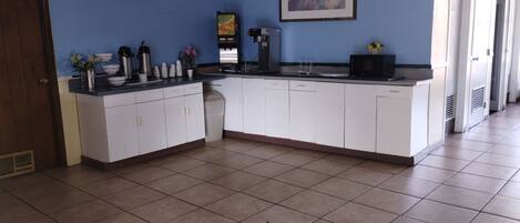 A kitchen with white cabinets, a coffee machine, and a microwave.