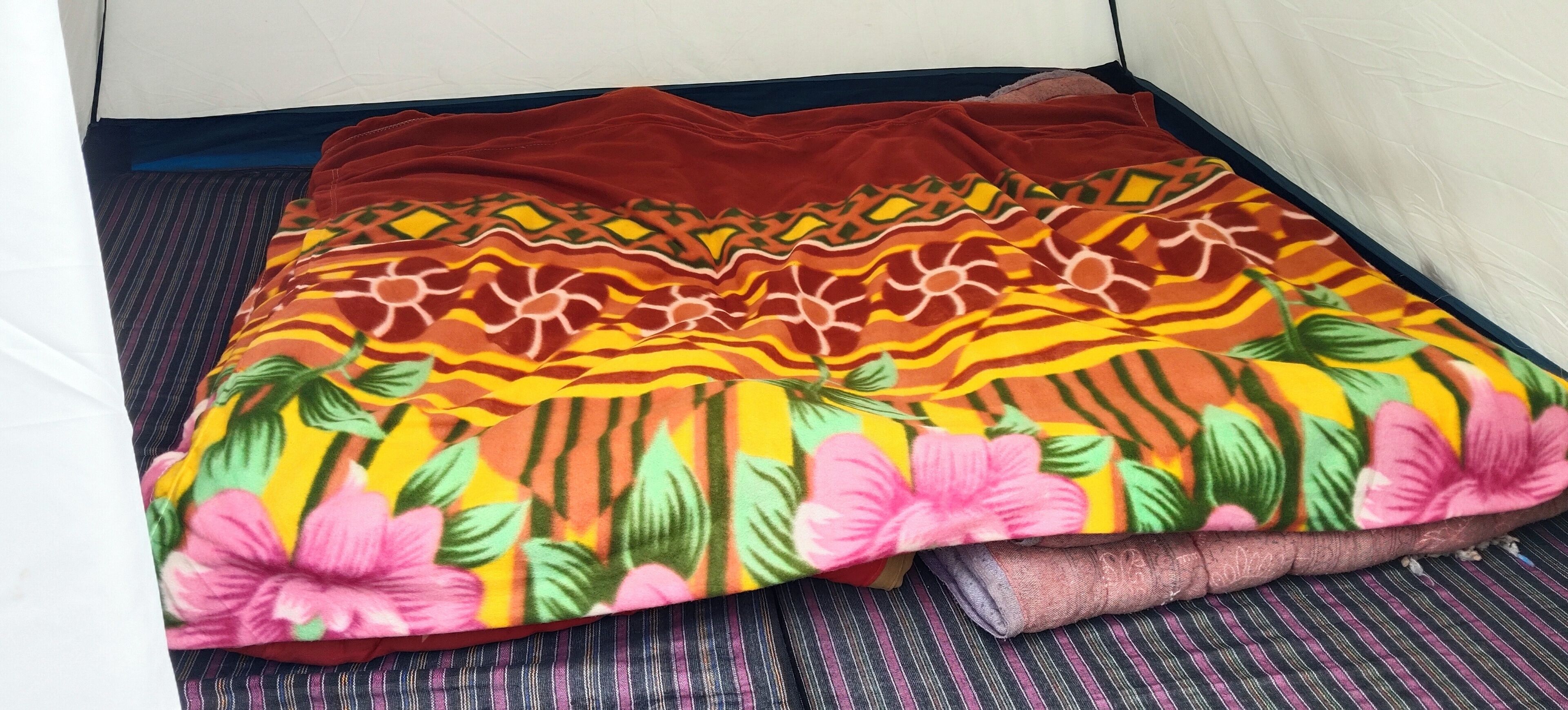 A bed with a floral-patterned blanket and a striped pillow.