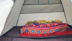 A tent with a bed inside, featuring a colorful blanket and striped bedding. - YATRA DHAM CAMP KEDARNATH  (Kedarnath)